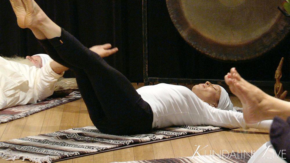 leg lifts with gong in background yoga hatha pradupadha vinyasa